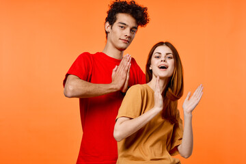 guy and girl in colorful t-shirts fun studio orange background