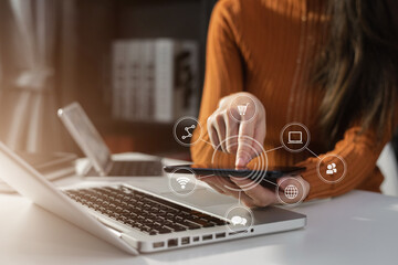 Businesswomen or Designer using tablet with laptop and document on desk in modern office with virtual interface graphic icons network diagram.