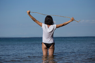Obraz premium woman in black bikini and white shirt in shallow water, summer holiday vacation in natural beach