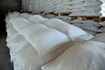 The grain sacks in the warehouse are stacked in straight rows.