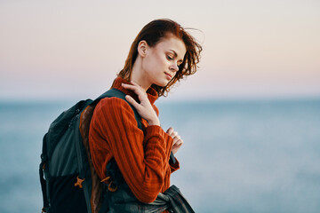 woman woman hiker with a backpack near the sea in the mountains in nature and a red sweater model