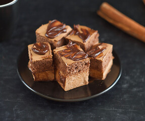 Pieces of chocolate cake lie in a saucer, next to cinnamon sticks