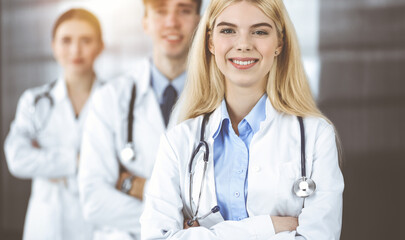 Group of three young doctors standing as a team with arms crossed in modern clinic and ready to help patients. Medicine concept