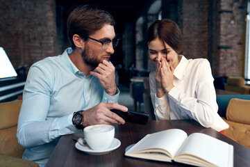 business man and woman sitting at a table in a cafe and looking at the phone