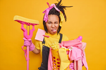 Displeased busy house cleaner smirks face with aversion holds mop for washing floor collects dirty...