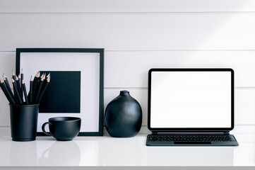 Black and white reative workspace concept with tablet and supplies.
