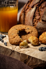 Biscuits, bread and a glass of juice on a wooden stand on a brown background