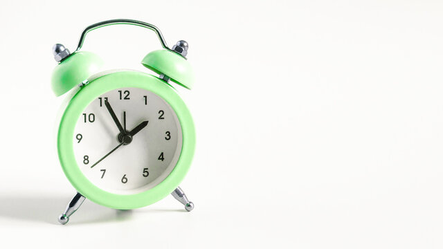 classic mechanical alarm clock green color on a light background close up copy space
