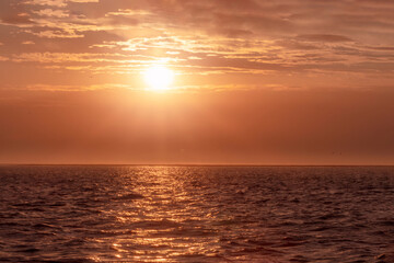Colorful red sunset and bright sun on the horizon of the ocean beach.