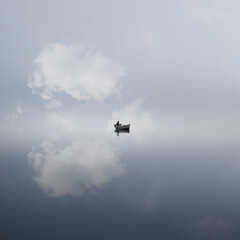Fisherman on a boat on the sea with long exposure and a blue sky reflecting on it