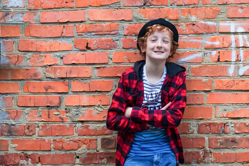 Empty space for the text. A boy 11-13 stands against a red brick wall. Soft focus.