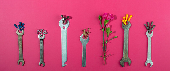Labor Day background concept, 1 May concept. Wrench and clove pink carnation flower on pink background.