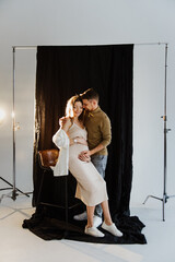 Beautiful young pregnant woman and man hugging and kissing in the studio.