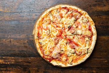 Fresh italian pizza with bacon, tomatoes, mushrooms and cheese on a wooden background.  Italian food. Space for text.