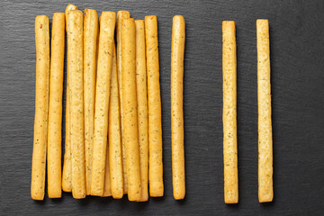 Homemade Italian Grissini Breadsticks on a black background. Traditional italian snack with herbs.  Space for text.