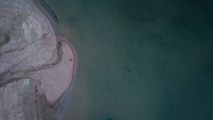 Beautiful aerial view of the boat driving on the ocean closer to the cliff on the shore