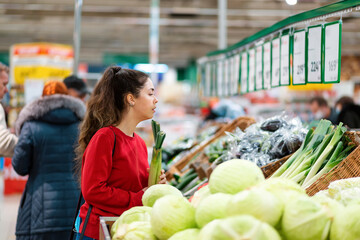 Shopping. Portrait of a young Caucasian woman choosing vegetables in a supermarket. The concept of shopping and consumerism