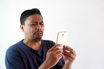 sad man crying looking at the phone, funny upset reaction asian guy with smartphone, unhappy...
