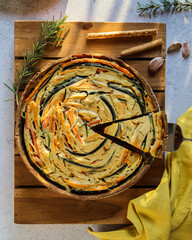 Italian spiral vegetable pie on a wooden tray. The pie is made with zucchini, sweet potatoes and carrots. Top view.