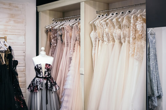 Beautiful collection wedding dresses various colors hanging on a hanger in a clothing store shop shopping mall. Fashion fancy stylish exhibition. Image with copy space.
