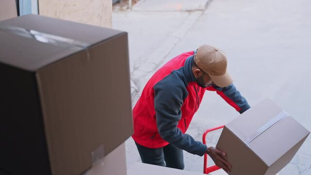 Young man unloading cardboard boxes from the truck. High quality 4k footage