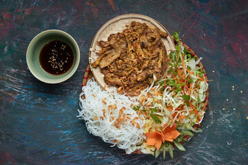 A large portion of traditional grilled duck with rice noodle, served with soy sauce and salads