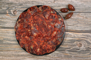 Portion of 100% acorn-fed Iberian chorizo from Extremadura decorated with acorns on wooden background