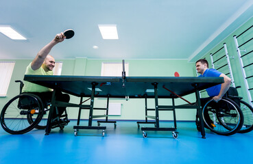 Adult disabled men in a wheelchair playing table tennis