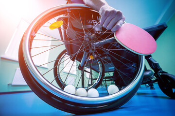 Disabled man in a wheelchair play at table tennis. Tennis balls fixed in a wheel