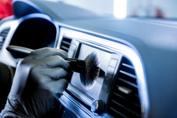A car service worker cleans the car console with a special brush