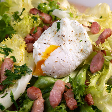 Recipe for poached egg cut with a knife, bacon and salad, High quality photo