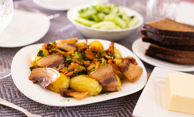 traditional rustic dish. fried potatoes with chanterelle mushrooms and pork brisket with herbs