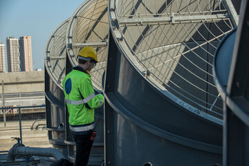 engineer under checking the industry cooling tower air conditioner is water cooling tower air chiller HVAC of large industrial building to control air system. 