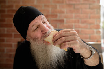 Portrait of happy mature man with long gray beard eating taco
