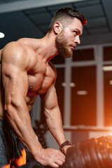 Attractive bodybuilder with muscular body type. Sportsman standing near sport equipment in modern...