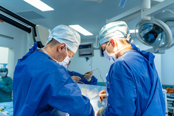 Fototapeta na wymiar Group of surgeons doing operation in modern hospital room.