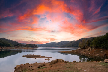 The lake and the sunset. View of the lake and forest at sunset. Red sky Cloudy sky landscape.