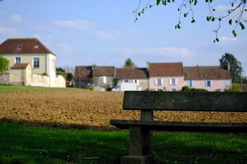 A lonely bench and a small village in the background in France