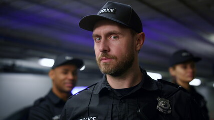 Police man in cap posing at camera. Serious police officer looking at camera