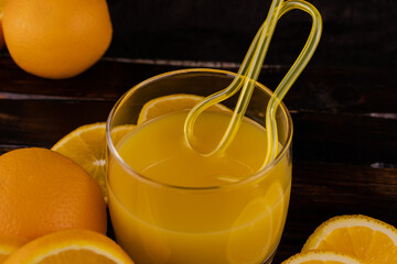 Juice in a glass with a straw and juicy oranges