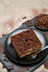 Portion of Traditional Italian Tiramisu dessert on grey concrete background