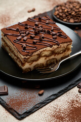Portion of Traditional Italian Tiramisu dessert on grey concrete background