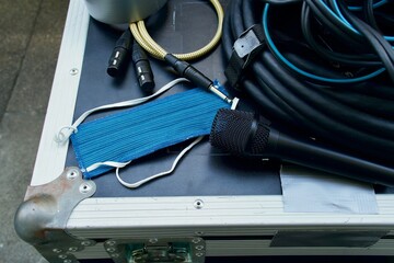 Blue mask laying on a case with some cables (XLR and 1/4" jack), a microphone and a roll of tape, medical mask for protection from all kinds of diseases