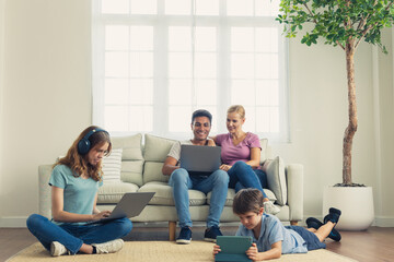 A parent and Children using a laptop, smartphone in the living room.