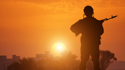 Silhouette Of A Solider Saluting Against coastal town . Concept - protection, patriotism, honor.