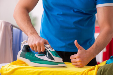 Young man husband doing ironing at home