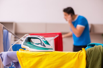 Young man husband doing ironing at home