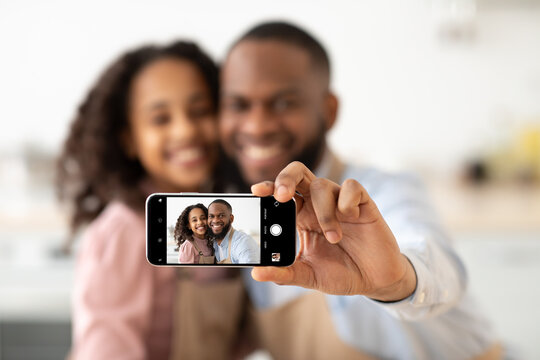 Cheerful african american father taking selfie with smiling daughter