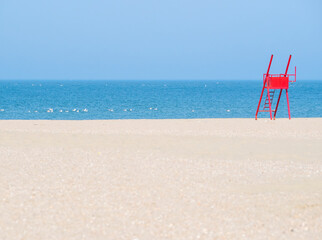 Red lifeguard chair on an empty beach.