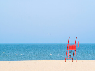 Red lifeguard chair on an empty beach.